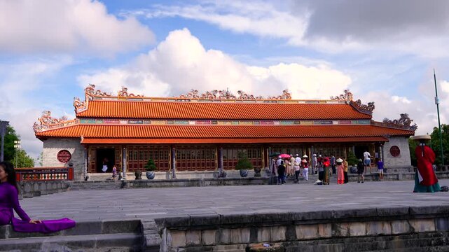 Grand Thai Hoa Palace featuring intricate dragon roof details, striking red lacquered doors, and carved grey stone pillars under sunlight.