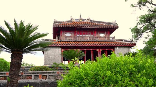 Minh Lau Pavilion viewed across a stone bridge, surrounded by lush gardens and pines at Minh Mang Tomb.