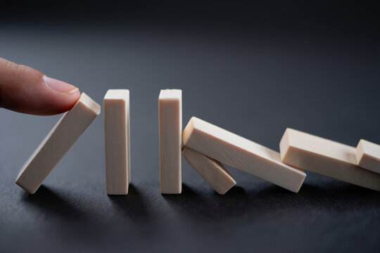 Domino Effect Concept with Hand Pushing First Piece, Chain Reaction with Falling Blocks on Dark Backdrop, Cause and Effect Game