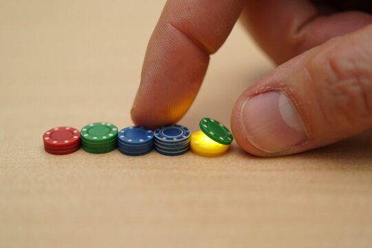 Hand Flipping Colorful Chips in Row on Bright Background, Poker Chips Close Up, Gambling and Game Night Concept, Start Chain Reaction