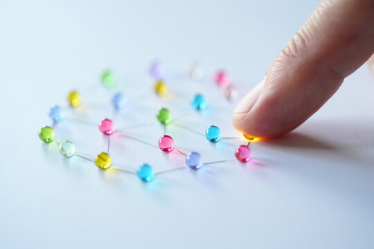 Finger Touching Connected Network of Colorful Pins on White Surface Representing Complex Relationships Social Media Interconnection and Communication - Powered by Adobe