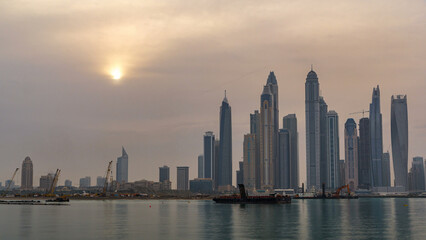 Fototapeta premium Panorama of modern skyscrapers in Dubai city at sunrise timelapse from the Palm Jumeirah Island.