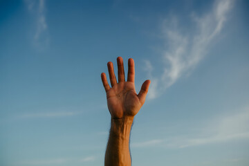 Uplifting hand reaching towards a bright sky, conveying hope, aspiration, and connection to nature, perfect for inspirational messages and wellbeing campaigns