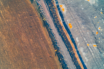 Abstract drone view highlighting the sharp boundary between healthy brown farmland and a gray...