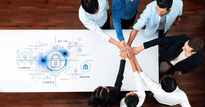 A diverse group of professionals joins hands over a table, symbolizing teamwork and collaboration in cybersecurity strategy with a digital lock graphic, showcasing commitment to data protection. Trope