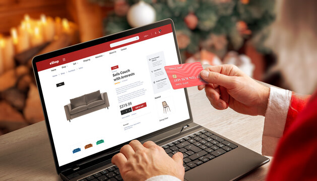Santa shopping online on laptop with credit card in cozy Christmas interior, perfect for ecommerce promotions, holiday marketing, winter retail and digital shopping themes