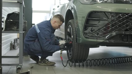Professional auto mechanic changing and balancing car wheel in a tire fitting workshop