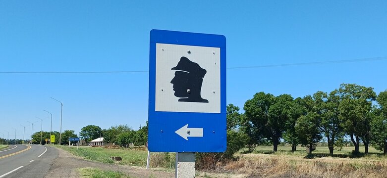 Policia Schild Uruguay &ndash; Polizei Hinweiszeichen an Landstra&szlig;e, blaues Verkehrsschild, l&auml;ndliche Umgebung