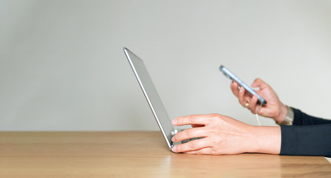 Person hands using smartphone connected to a laptop on wooden desk, symbolizing file transfer, data syncing, mobile technology,Businesswoman holding phone remote online work communication to customers
