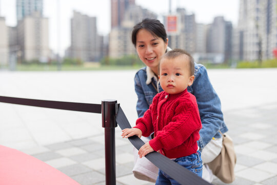 Baby looking at exhibit with mother behind