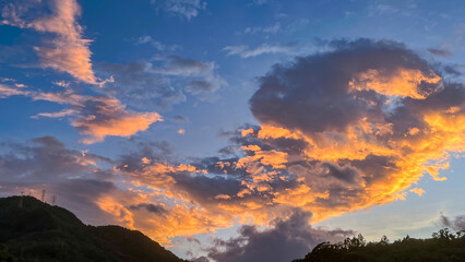 Intense orange and golden sunrise clouds glowing dramatically above the dark mountain ridges of Wulai in New Taipei City Taiwan at early dawn.