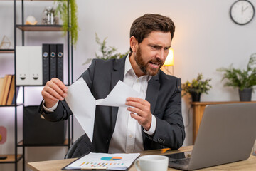 Middle-aged businessman at home office finds error rips draft opens new document on laptop then...