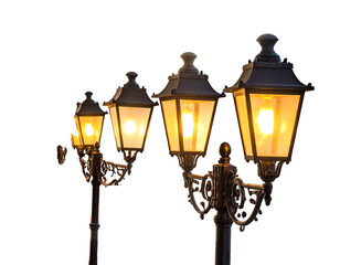 Four ornate street lamps with illuminated amber lights against a dark, empty background. The lamps diminish in size