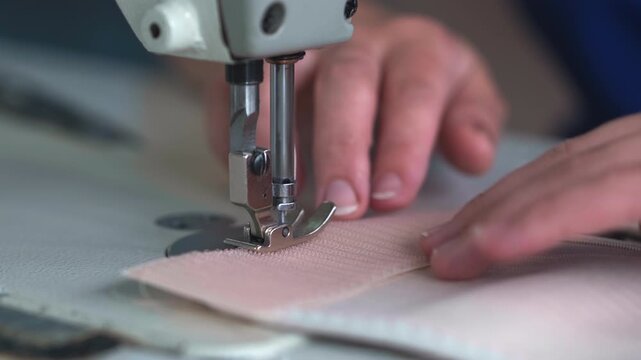 A close view shows hands guiding hook and loop compatible loop fabric under the needle of an industrial sewing machine, forming a clean seam with steady motion and precise control