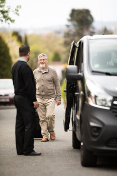 Senior man getting picked-up for his airport transfer by a private shuttle service driver. Commericial trasfer cargo transportation company fleet. Vip charter
