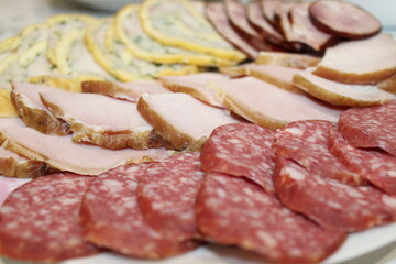 Assorted deli meats arranged on a platter at a festive gathering in a cozy kitchen setting