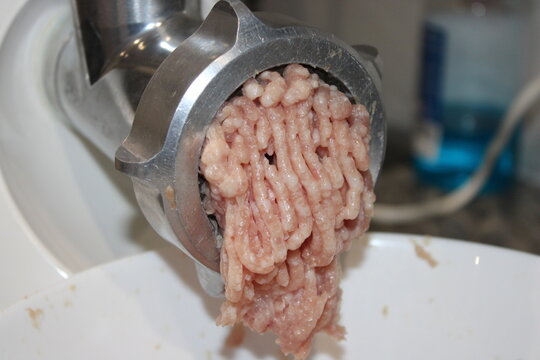 Grinding meat in a kitchen with a meat grinder for fresh ground meat preparation