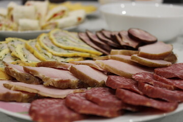 Sliced meats and rolled appetizers arranged on a plate for a gathering in a cozy kitchen