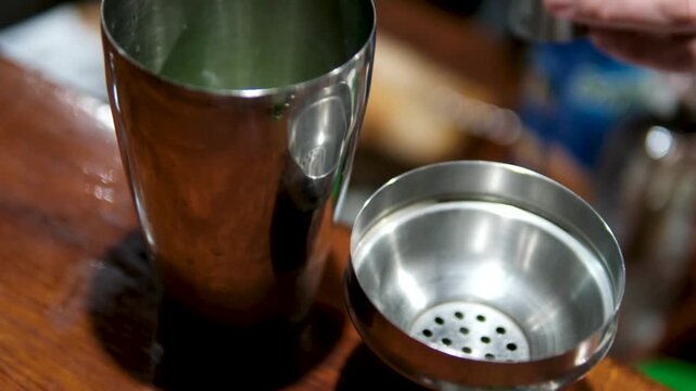 Professional bartender masterly creating a cocktail in modern bar. Experienced barman adding syrip into shaker using jigger - food and drink, nightlife.