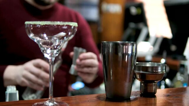 Professional bartender masterly creating a cocktail in modern bar. Experienced barman adding syrip into shaker using jigger - food and drink, nightlife.