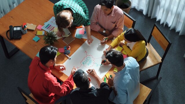 Top down view of smart business team in casual cloth brainstorming marketing idea and writing mind map together. Professional creative people using mind map to share and exchange idea. Convocation.