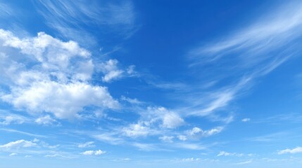 Fluffy white clouds drift lazily in a clear blue sky during a sunny afternoon. The scene evokes a sense of peace and openness in nature.