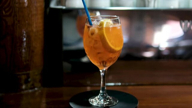 Glass of apperol spritz cocktail with orange slice on blue background. Closeup of summer drink, zoom in. High quality 4k footage