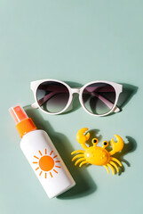 Summer Flat Lay with Sunscreen, Sunglasses and Toy Crab on Mint Background