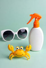 Summer Flat Lay with Sunscreen, Sunglasses and Toy Crab on Mint Background