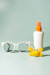 Summer Flat Lay with Sunscreen, Sunglasses and Toy Crab on Mint Background