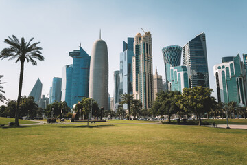 The high-rise district of Doha seen from Hotel Park, with green lawn and artificial hill in the foreground. Skyscrapers and palms