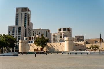 Architecture of Doha. Al Koot Fort at Doha, Qatar. Vintage white Ford with the flag of Qatar on a blue sky background.