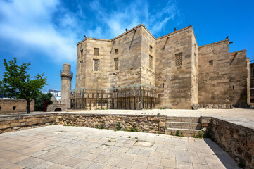 View of the Shirvanshah Palace complex in Baku Azerbaijan showing domes and stone architecture under a bright blue sky.