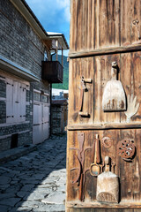 Weathered wooden blacksmith shop door in Lahij, Azerbaijan, with rustic metal tools and handmade details.