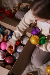 Child and box of Christmas decorations