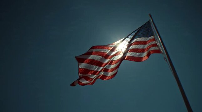 American flag waving on veterans day with backlit sun against dark blue sky