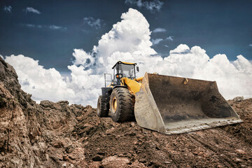 A large excavator digs into the earth at a construction site. The machine's bucket is ready to lift...