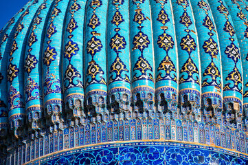 Close-up view of the richly decorated tiled dome of the Mausoleum of Khoja Ahmed Yasawi in Turkestan, Kazakhstan, showing intricate Islamic architectural design against the sky.