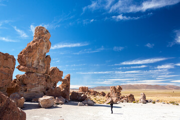 A traveler takes photographs among unusual rock formations in a rocky valley near Uyuni, Bolivia.