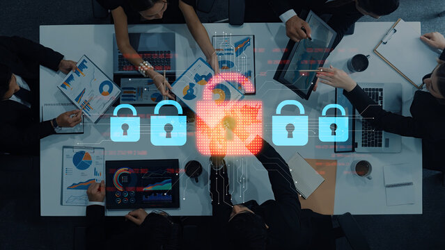 A team of professionals engages in a business meeting focused on cybersecurity strategies. Digital elements representing data protection and security are visible, enhancing the discussion. Trope - Powered by Adobe