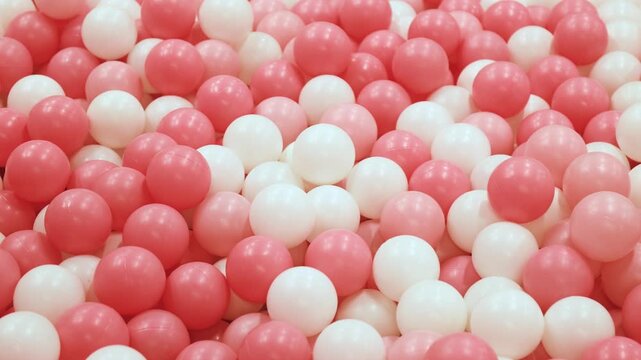 Toy ball, Pink and white play balls densely filling a ball pit, Plastic ball in a ballpit, Colorful ball in a playground, Creating a bright, Cheerful, Playful atmosphere ideal for kids themes and fun