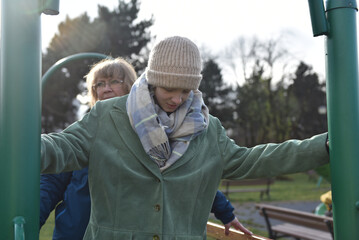 Teenager daughter and mother holding onto green poles in an outdoor park