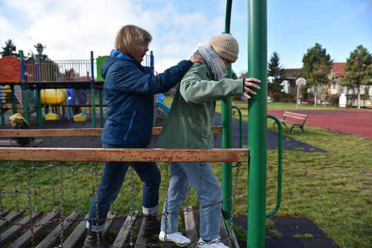 Two women assisting each other on an outdoor obstacle course