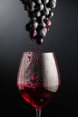 Red wine flows down the grape cluster into the glass.