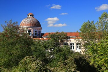 Abandoned dome building with overgrown vegetation and blue sky in background