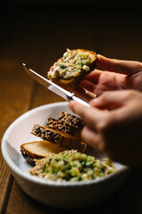 Hands holding toast with tuna spread and cucumber relish