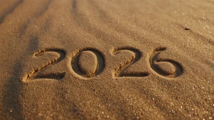 The year 2026 written in the sand on a beach, symbolizing the passage of time and future events.