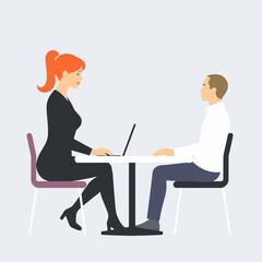 A businesswoman with a laptop conducts a job interview with a male candidate at a table.