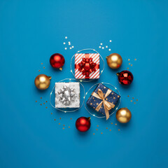 Modern Christmas Flat Lay Composition with Assorted Wrapped Gifts, Red and Gold Ornaments, Star Lights, and Glitter Centered on a Bright Blue Background – Holiday Sale, Winter Season, Greeting Cards