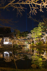 Beautiful illuminated Kodai-ji temple with trees foliage reflected in water during springtime illumination show in Kyoto, Japan.